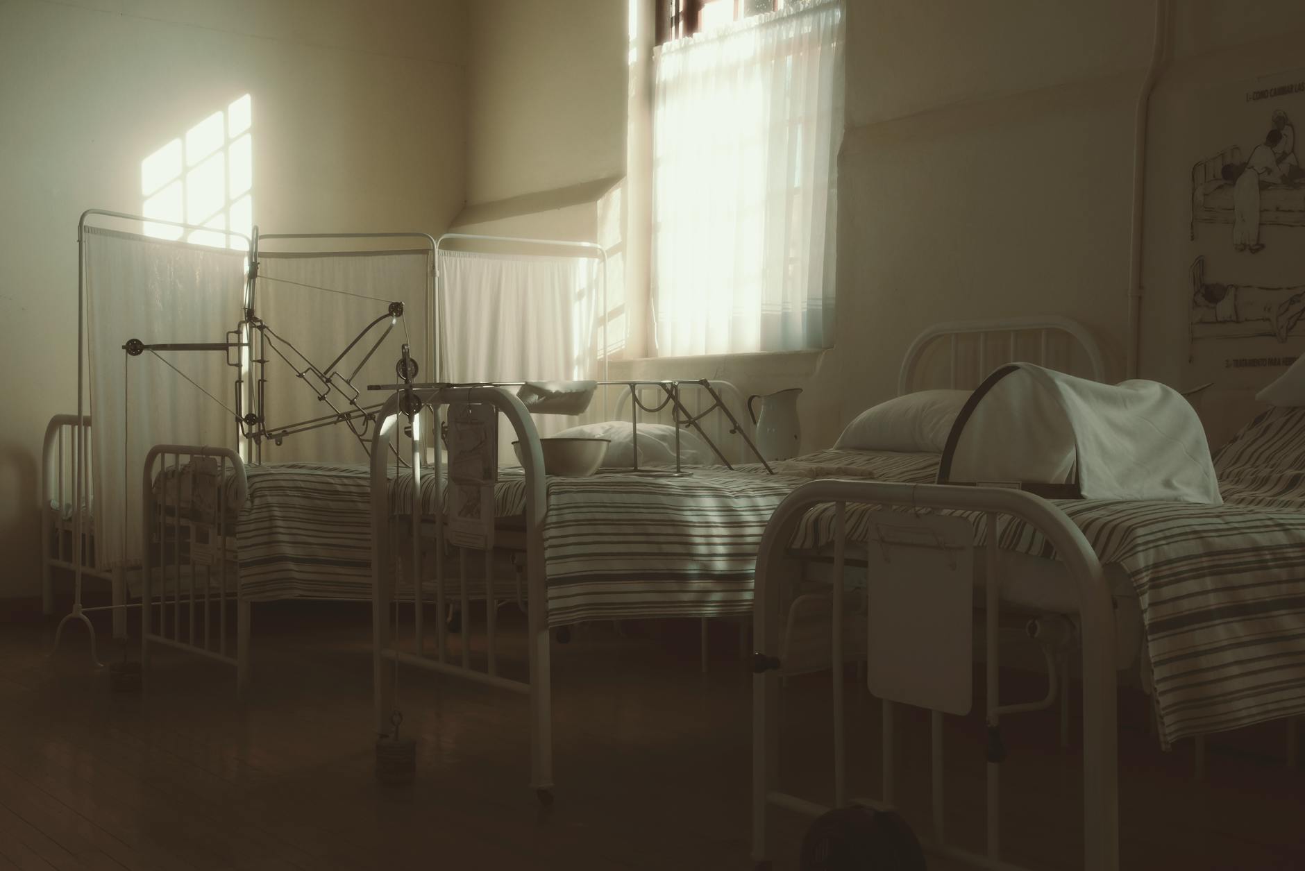 Puste łóżka i aparatura w przyciemnionym, vintage’owym pokoju szpitalnym