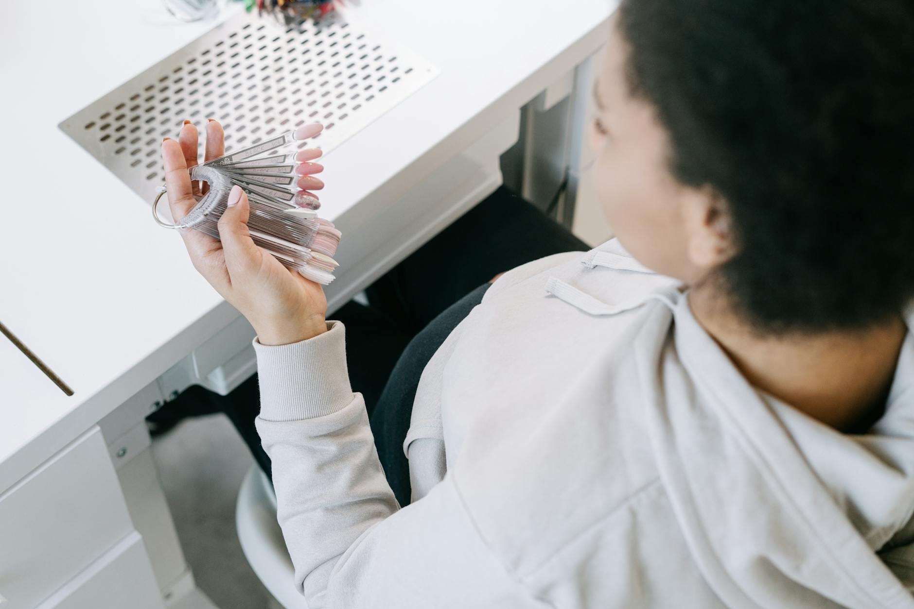 Ciężarna kobieta trzyma próbki lakierów, wybiera manicure na randkę