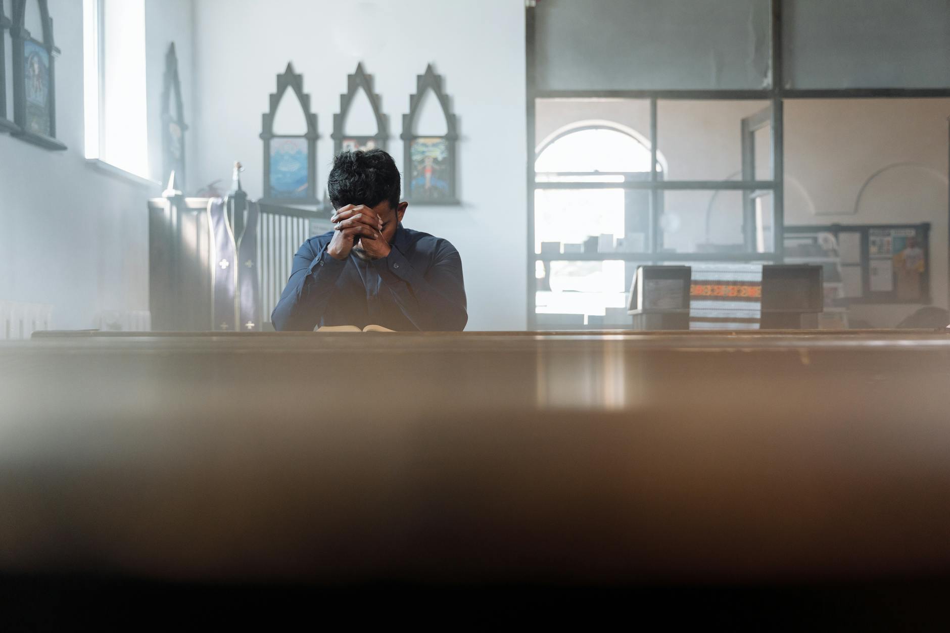 Mężczyzna modli się w nasłonecznionym pokoju, pogrążony w zadumie