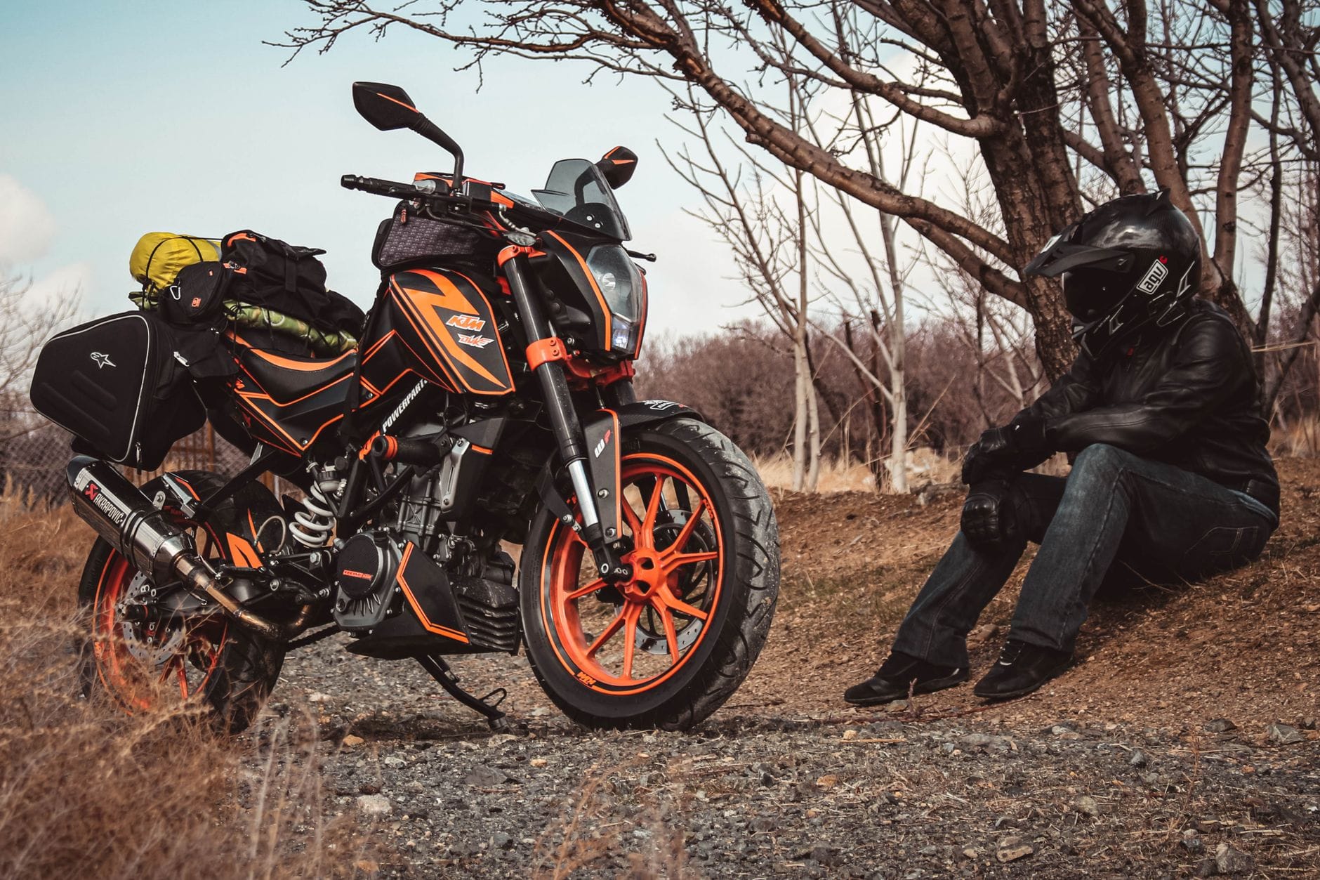 Motocyklista w ubraniu ochronnym odpoczywa przy zapakowanym KTM na drodze